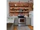 Bright kitchen with stainless steel range, open shelving, and decorative brick backsplash at 2424 N Clay St, Denver, CO 80211