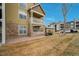 Condominium featuring dual balconies with a stone facade and tan siding at 6021 W Castlegate Dr # E18, Castle Rock, CO 80108