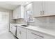 Bright kitchen features white cabinets, modern appliances, tile backsplash, and window at 1665 Yukon St, Lakewood, CO 80214