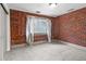 Bedroom features exposed brick wall, modern curtains, and neutral carpet at 3211 Zuni St # 14, Denver, CO 80211