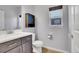 This bathroom features a modern vanity, toilet, and a window offering natural light, enhanced by a wall cabinet for storage at 7888 Tejon St, Denver, CO 80221