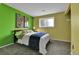 Bedroom featuring green accent wall, window letting in natural light, and contemporary wall art pieces at 16025 E Warren Pl, Aurora, CO 80013