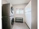 Tiled laundry room with modern stacked washer and dryer, storage units, and a window for natural light at 18155 Flowered Meadow Ln, Monument, CO 80132