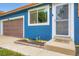 Close up of home's entrance highlighting the blue stucco, brown garage door, and nicely landscaped entry at 18662 E Brown Pl, Aurora, CO 80013