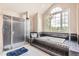 Bright bathroom with a soaking tub set in a dark tile surround, and separate glass enclosed shower at 7758 Edgewater Ct, Lone Tree, CO 80124