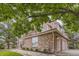 Side exterior view of home with brick facade, three-car garage, and mature trees at 7758 Edgewater Ct, Lone Tree, CO 80124