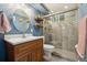 Stylish bathroom featuring a wood vanity, circular mirror, and a glass enclosed shower with modern tiling at 1667 S Balsam Ct, Lakewood, CO 80232