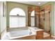 Bright bathroom features a bathtub under an arched window and a glass-enclosed shower at 11951 Singing Winds St, Parker, CO 80138