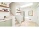 This brightly lit kitchen has stone floors, a stainless fridge, floating wood shelves, and light-green cabinets at 250 S Ogden St, Denver, CO 80209