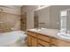 Bright bathroom features a tub with tiled surround, vanity with double sinks, and a large mirror at 9387 Ashbury Cir # 203, Parker, CO 80134