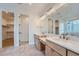 Bathroom with dual sinks, a large mirror with custom lighting, and a walk-in closet in the background at 945 Saint Andrews Ln, Louisville, CO 80027