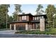 Striking modern home featuring a stone accent wall, sleek black trim, two-car garage, and wood siding amongst mature trees at 945 Saint Andrews Ln, Louisville, CO 80027