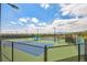 Outdoor tennis courts with fences and lighting with neighborhood in the distance and cloudy blue sky at 945 Saint Andrews Ln, Louisville, CO 80027