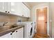 Functional laundry room with white cabinetry, a utility sink, granite countertops, and modern LG washer/dryer at 1555 Genesee Ridge Rd, Golden, CO 80401