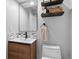 Small powder room with wood vanity, modern sink, decorative mirror, and open storage shelves at 9939 E Aberdeen Ave, Englewood, CO 80111