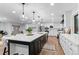Open kitchen with white cabinets, stainless appliances, and a large island with seating and pendant lights at 9939 E Aberdeen Ave, Englewood, CO 80111
