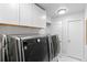 Bright laundry room with side-by-side washer and dryer and white cabinets for storage at 9939 E Aberdeen Ave, Englewood, CO 80111