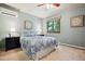 Cozy bedroom with a blue patterned comforter, ceiling fan, and large window with green outdoor views at 14150 Foothill Ln, Golden, CO 80401