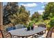 Outdoor dining set amongst trees, a blue sky, and summer flowers at 14150 Foothill Ln, Golden, CO 80401