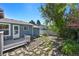 Backyard deck surrounded by stone pavers, garden beds, and blue house siding at 8679 Apache Plume Dr, Parker, CO 80134