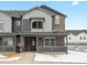 Charming two-story townhouse with brick and gray siding, showcasing a welcoming front porch and modern design at 6571 N Malaya St, Aurora, CO 80019