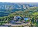 Aerial view showcases a stunning pool and clubhouse area surrounded by mountains and lush trees at 25601 Centennial Trl, Golden, CO 80401