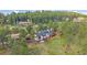 Aerial view of a multi-story home with a dark roof nestled among trees and a lush green landscape at 25601 Centennial Trl, Golden, CO 80401