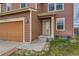 Close up view of the front door and attached two car garage with landscaping at 303 Diablo Pl, Brighton, CO 80603