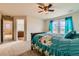 Primary bedroom features carpet, large windows with curtains, and ceiling fan, leading to en-suite bathroom at 303 Diablo Pl, Brighton, CO 80603