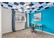 Stylish bedroom features a striking blue accent wall, checkered ceiling, and a cozy workspace near the bright window at 16402 E Tennessee Ave, Aurora, CO 80017