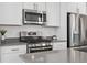 Modern kitchen featuring stainless steel appliances, white cabinets, and gray countertops at 12314 Hayloft Ln, Thornton, CO 80241