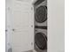 Modern laundry room features a stacked washer and dryer with a white door at 12314 Hayloft Ln, Thornton, CO 80241