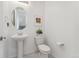 Clean powder room featuring a pedestal sink, toilet, oval mirror, and neutral decor at 12314 Hayloft Ln, Thornton, CO 80241