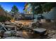 Backyard featuring a patio with outdoor seating, a grill, and a tranquil rock water feature at dusk at 8406 Winter Berry Dr, Castle Pines, CO 80108