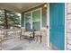 Cozy front porch with seating, a stylish blue door, stone accents, and an exterior light fixture at 8406 Winter Berry Dr, Castle Pines, CO 80108