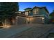 Three-car garage with an expansive driveway, exterior stone detail, and a well-maintained lawn at 8406 Winter Berry Dr, Castle Pines, CO 80108