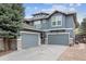 Three-car garage with an expansive driveway, exterior wood and stone detail, and a well-maintained lawn at 8406 Winter Berry Dr, Castle Pines, CO 80108