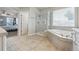 Bright primary bathroom with a glass enclosed shower, soaking tub, and tiled flooring at 8406 Winter Berry Dr, Castle Pines, CO 80108