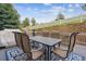 Outdoor dining set on a deck with a stone retaining wall and white fence, perfect for enjoying meals outside at 8406 Winter Berry Dr, Castle Pines, CO 80108