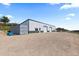 A large metal building with ample parking space on a gravel lot, featuring garage doors and a container at 15295 E Cherry Creek S Rd, Larkspur, CO 80118