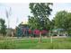 Community playground with red, green, and yellow play equipment on a grassy lawn at 4746 Raven Run, Broomfield, CO 80023