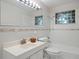 All-white bathroom featuring glass block windows, a large mirror, a vanity, and a bathtub with shower at 4580 S Huron St, Englewood, CO 80110
