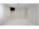 Neutral bedroom with carpet, a wall-mounted television, a door, and white baseboards at 4580 S Huron St, Englewood, CO 80110