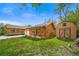 Spacious backyard with a log cabin home, shed, lush green lawn, and mature trees at 1415 Isabell St, Golden, CO 80401