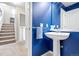 Half-bathroom with vibrant blue walls, a white pedestal sink, and an adjacent carpeted stairway at 3748 Oakwood Dr, Longmont, CO 80503