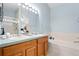 Bathroom featuring a double vanity, with a large framed mirror with Hollywood-style vanity lighting, a bathtub and separate shower at 3748 Oakwood Dr, Longmont, CO 80503
