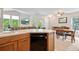 Open concept kitchen with stainless steel dishwasher and breakfast bar area overlooking dining area with natural light at 3748 Oakwood Dr, Longmont, CO 80503