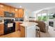Open kitchen boasts wood cabinets, an island with bar seating, and black appliances, with seamless flow to the living room at 3748 Oakwood Dr, Longmont, CO 80503