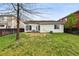 Large fenced backyard of home features lawn and mature trees, ideal for outdoor activities and relaxation at 4819 Jericho Ct, Denver, CO 80249
