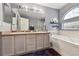 Well-lit bathroom featuring a soaking tub, double vanity, and tiled floors for a clean aesthetic at 4819 Jericho Ct, Denver, CO 80249
